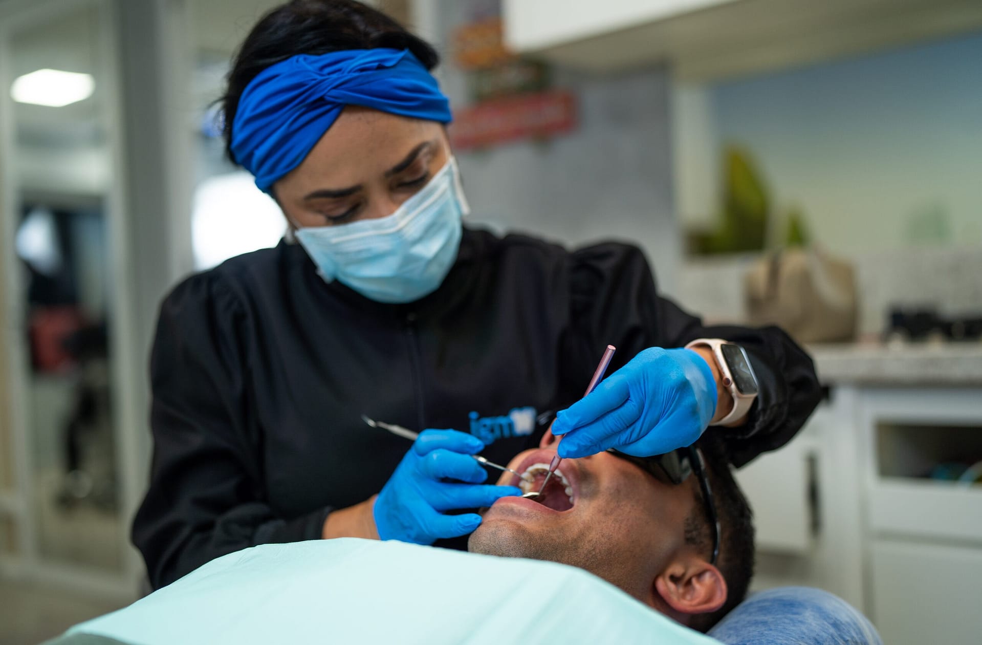 sobre a IGM, dentista com jaleco azul escuro fazendo atendimento odontológico